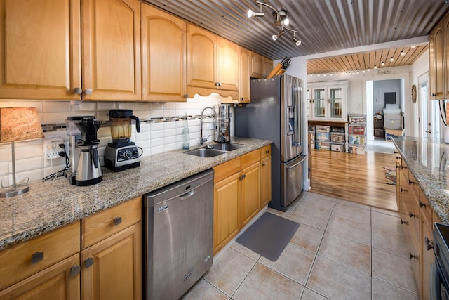 kitchen featuring stainless steel appliances, sink, track lighting, light stone countertops, and light wood-type flooring