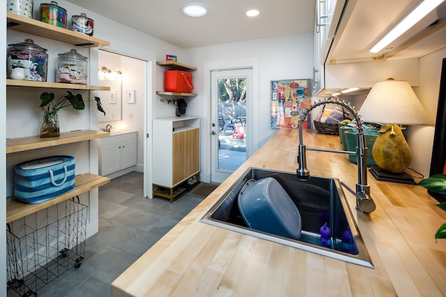 kitchen with white cabinets, sink, and butcher block countertops