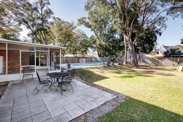 view of yard featuring a patio area, a sunroom, and a covered pool