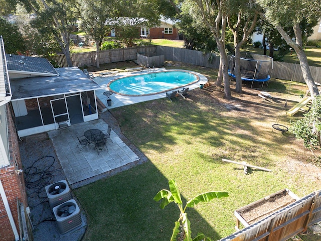 view of pool featuring cooling unit, a patio, a sunroom, a lawn, and a trampoline