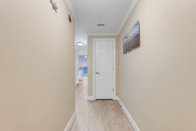 corridor with crown molding, baseboards, light wood finished floors, and visible vents