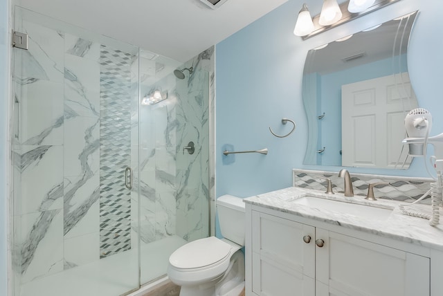 bathroom with toilet, decorative backsplash, vanity, and a shower with door