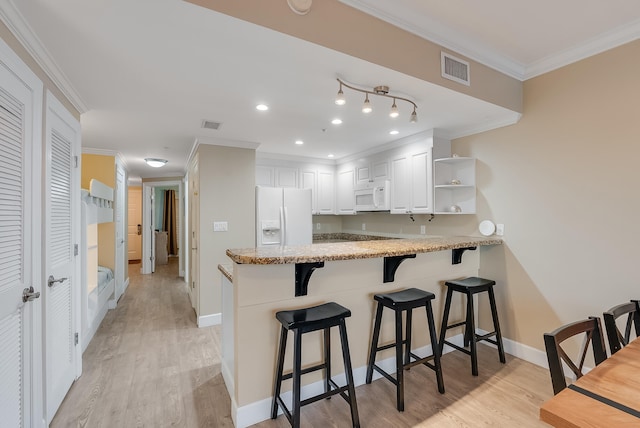 kitchen with white appliances, kitchen peninsula, white cabinets, crown molding, and light hardwood / wood-style flooring