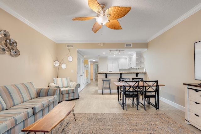 living room with ornamental molding, a textured ceiling, light wood-type flooring, and ceiling fan