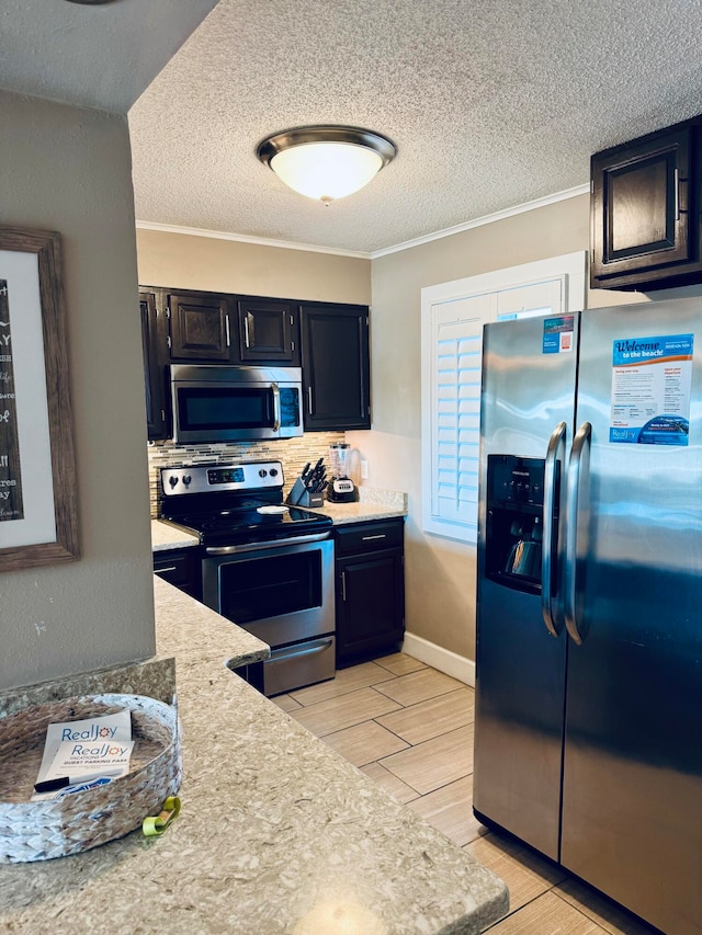 kitchen with decorative backsplash, appliances with stainless steel finishes, a textured ceiling, light hardwood / wood-style flooring, and ornamental molding