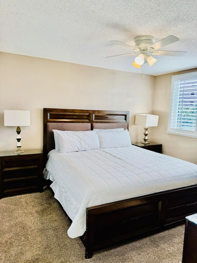 carpeted bedroom featuring ceiling fan and a textured ceiling