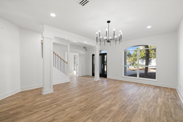 unfurnished living room featuring a notable chandelier and hardwood / wood-style floors