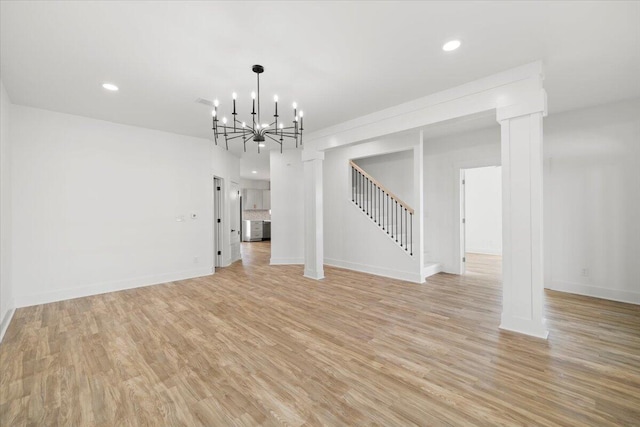 unfurnished living room with a notable chandelier and light hardwood / wood-style floors