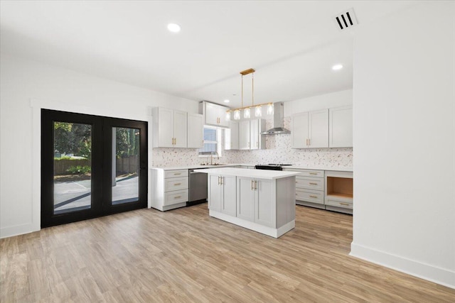 kitchen featuring a wealth of natural light, a center island, wall chimney range hood, and decorative light fixtures