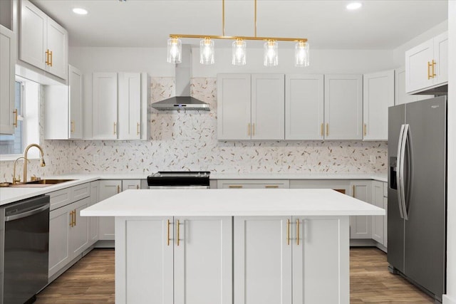 kitchen with a kitchen island, wall chimney range hood, hardwood / wood-style flooring, stainless steel appliances, and sink