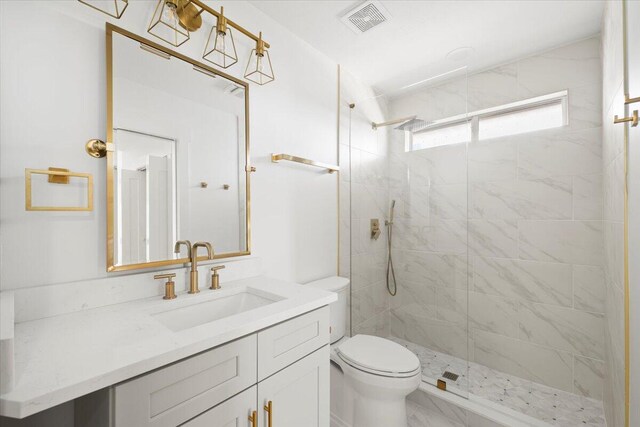 bathroom with vanity, a tile shower, and toilet