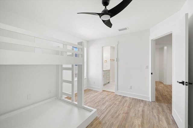 unfurnished bedroom featuring ceiling fan, ensuite bathroom, and light wood-type flooring