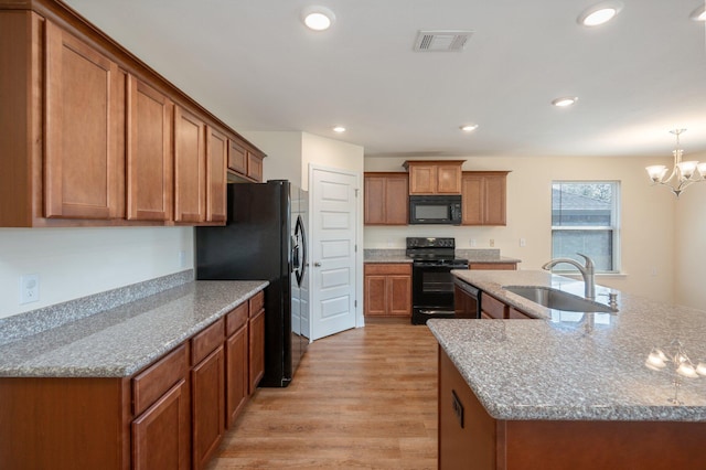 kitchen featuring light stone countertops, sink, black appliances, and light hardwood / wood-style flooring