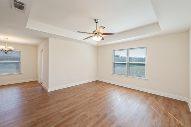 spare room featuring hardwood / wood-style flooring, a tray ceiling, and ceiling fan with notable chandelier