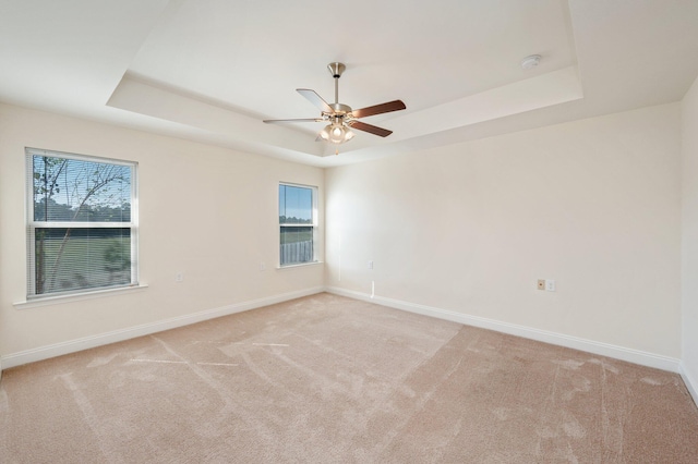 unfurnished room with light carpet, a tray ceiling, and ceiling fan