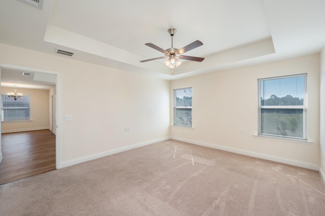 unfurnished room with a tray ceiling, a wealth of natural light, and carpet floors