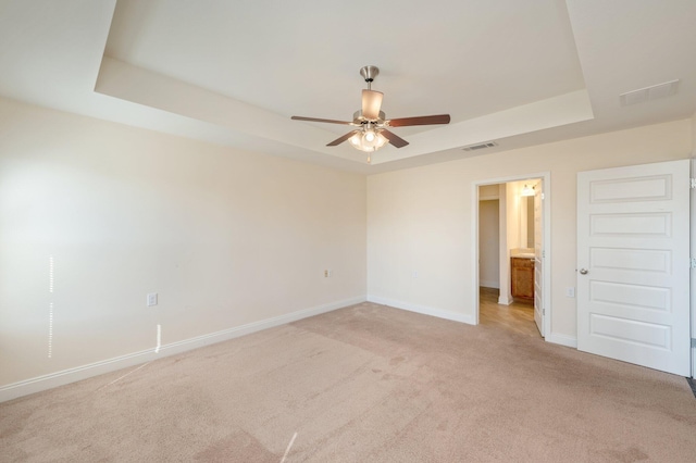 spare room featuring a tray ceiling and light colored carpet