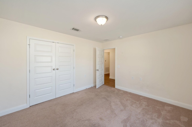 unfurnished bedroom with a closet and light carpet