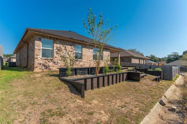 rear view of house with central AC and a yard