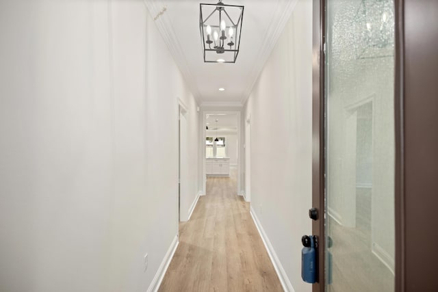 hallway with light wood-type flooring, crown molding, and a chandelier