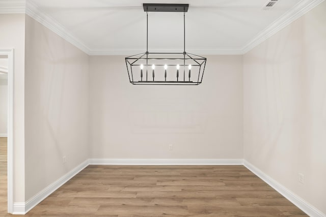 unfurnished dining area featuring hardwood / wood-style flooring, ornamental molding, and a chandelier