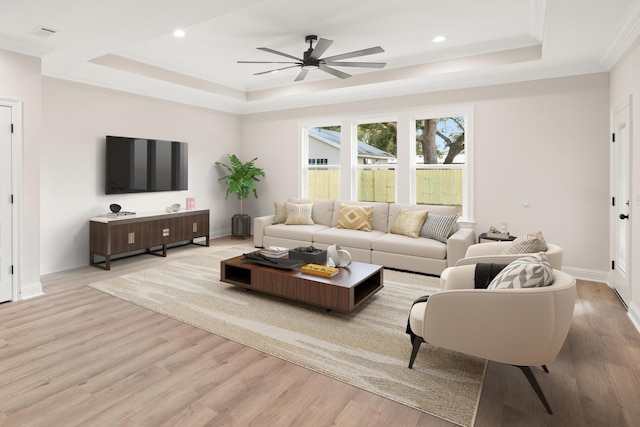 living room with ceiling fan, crown molding, light hardwood / wood-style flooring, and a tray ceiling