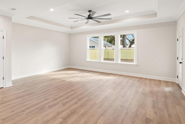 empty room featuring ceiling fan, crown molding, light hardwood / wood-style floors, and a raised ceiling