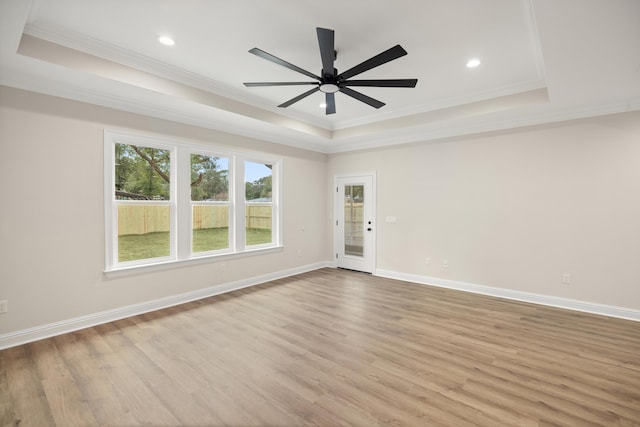 spare room featuring light wood-type flooring, ceiling fan, crown molding, and a tray ceiling