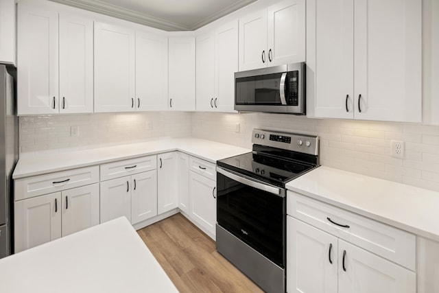 kitchen with white cabinets, appliances with stainless steel finishes, decorative backsplash, light wood-type flooring, and crown molding