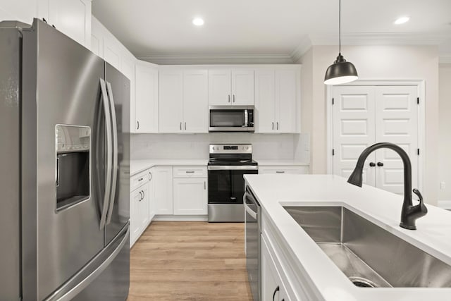 kitchen with appliances with stainless steel finishes, pendant lighting, white cabinetry, and sink