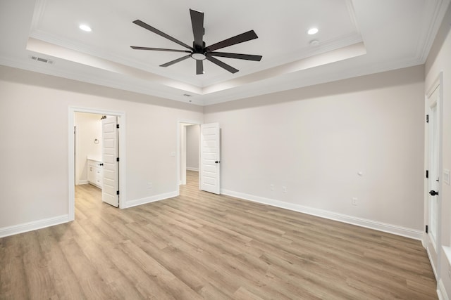 unfurnished bedroom featuring ceiling fan, ensuite bathroom, and a raised ceiling