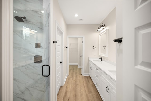 bathroom with wood-type flooring, walk in shower, and vanity