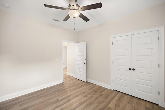 unfurnished bedroom with ceiling fan, a closet, and light wood-type flooring