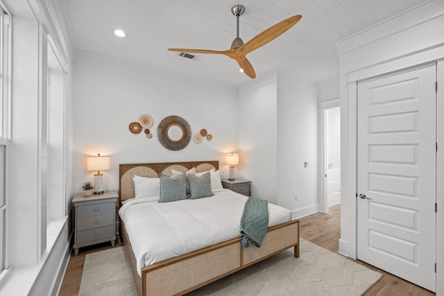 bedroom with ornamental molding, a closet, light hardwood / wood-style floors, and ceiling fan