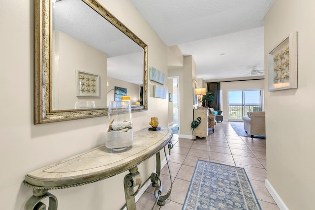 hallway with a textured ceiling and light tile patterned floors