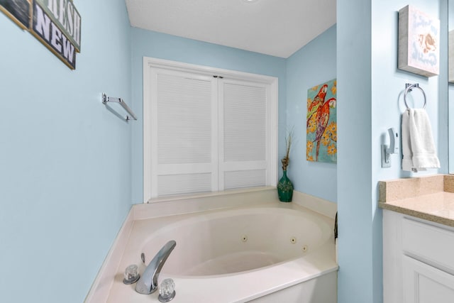 bathroom featuring vanity, a textured ceiling, and a bath