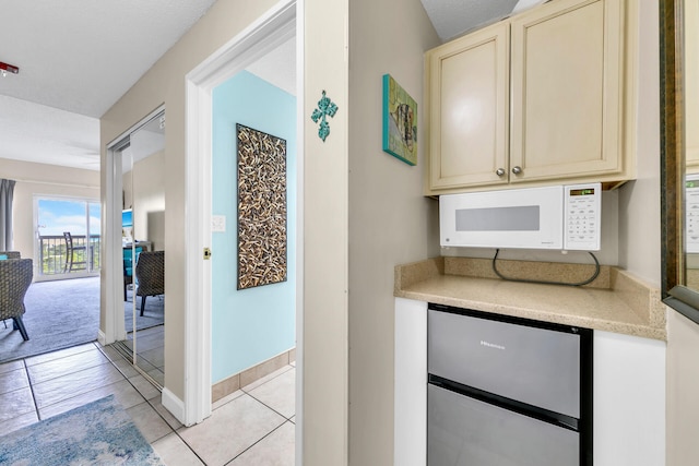 kitchen featuring light tile patterned flooring, cream cabinetry, and stainless steel refrigerator