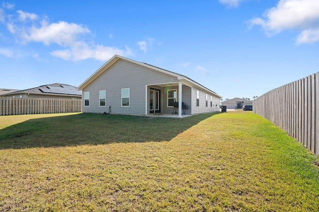 rear view of property featuring a patio and a yard