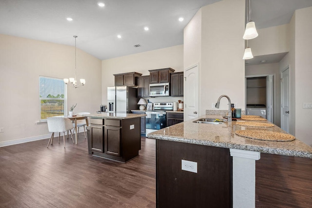 kitchen featuring a kitchen island with sink, stainless steel appliances, hanging light fixtures, and dark hardwood / wood-style flooring