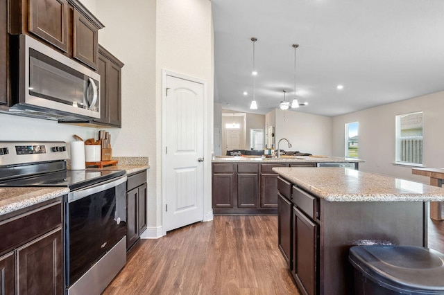 kitchen featuring appliances with stainless steel finishes, sink, a center island, dark hardwood / wood-style flooring, and dark brown cabinetry