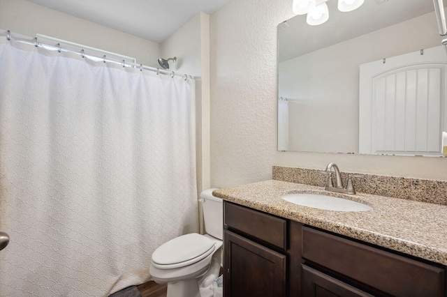 bathroom with toilet, walk in shower, and vanity