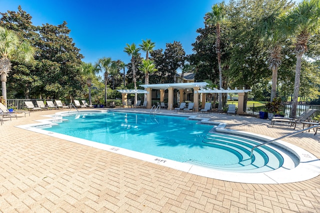 pool with fence, a pergola, and a patio area