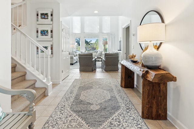 entryway with baseboards, stairs, and light tile patterned flooring