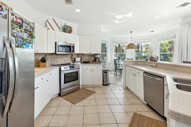 kitchen with appliances with stainless steel finishes, hanging light fixtures, white cabinetry, and tasteful backsplash