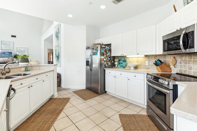 kitchen featuring white cabinets, appliances with stainless steel finishes, a sink, light countertops, and tasteful backsplash