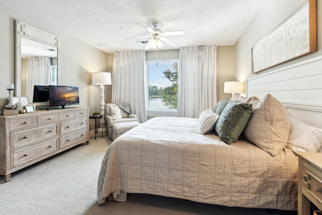 bedroom with light colored carpet, a textured ceiling, and ceiling fan
