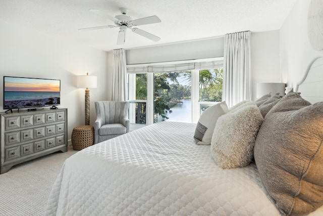bedroom with a water view, access to outside, a ceiling fan, and carpet flooring