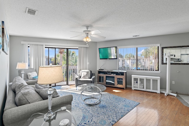 living room featuring hardwood / wood-style floors, a textured ceiling, a healthy amount of sunlight, and ceiling fan