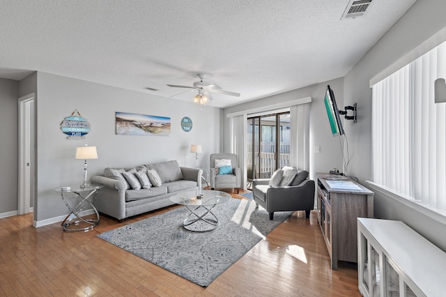 living room with a textured ceiling, wood-type flooring, and ceiling fan