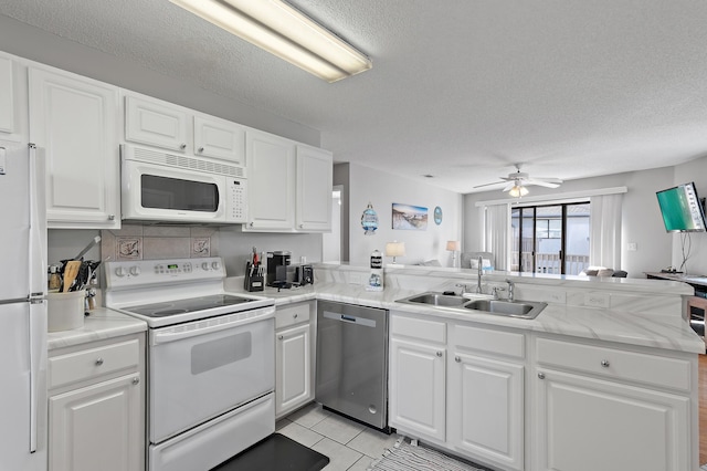 kitchen featuring white appliances, white cabinetry, sink, and kitchen peninsula